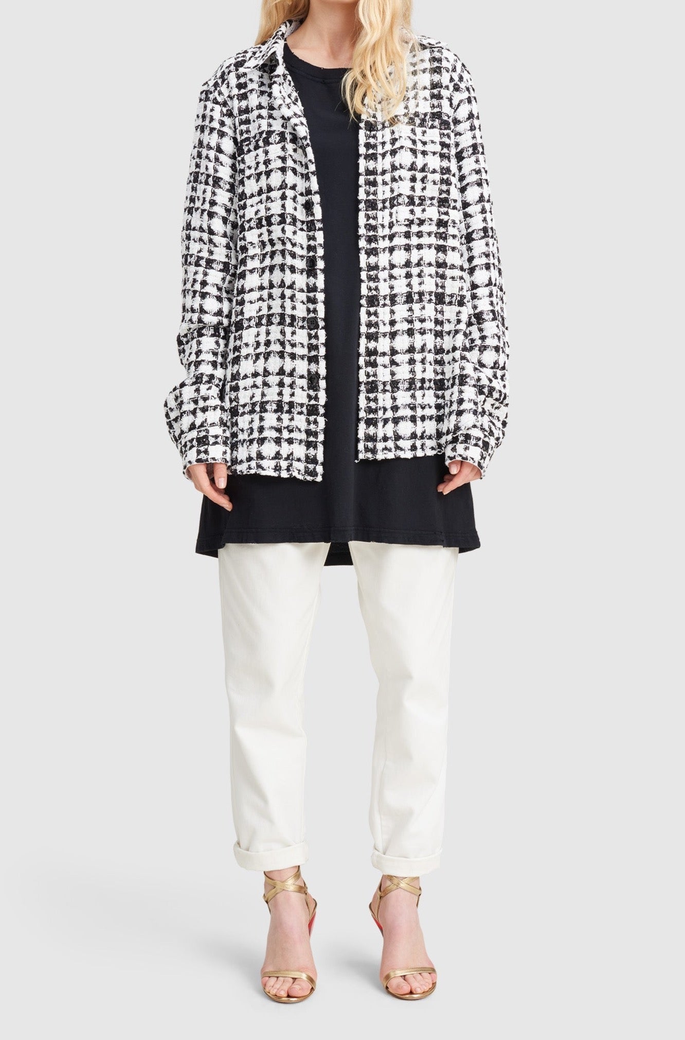 A woman is wearing a black and white checked tweed overshirt by Faith Connexion, a brand of luxury clothes